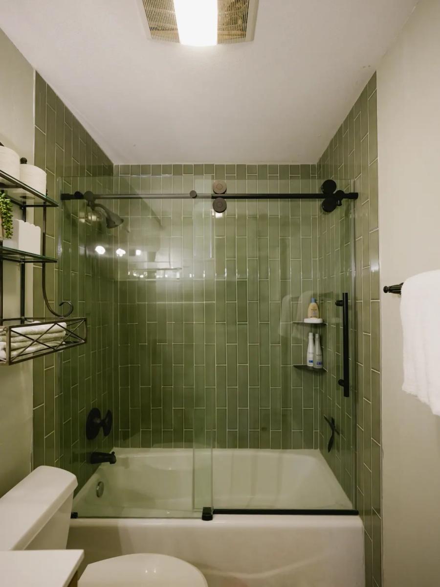 Green subway-tile shower with a glass slider
