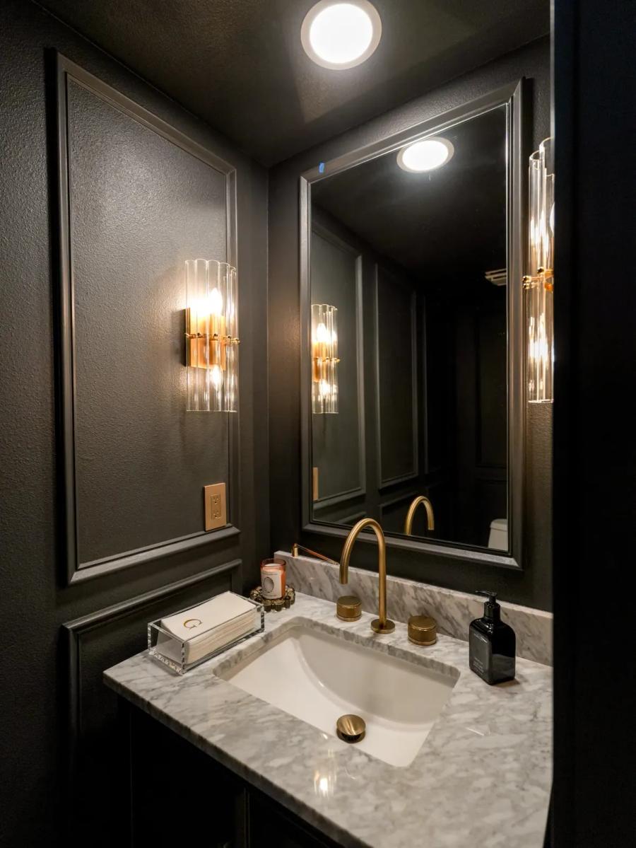 Black paneled powder room with a brass faucet