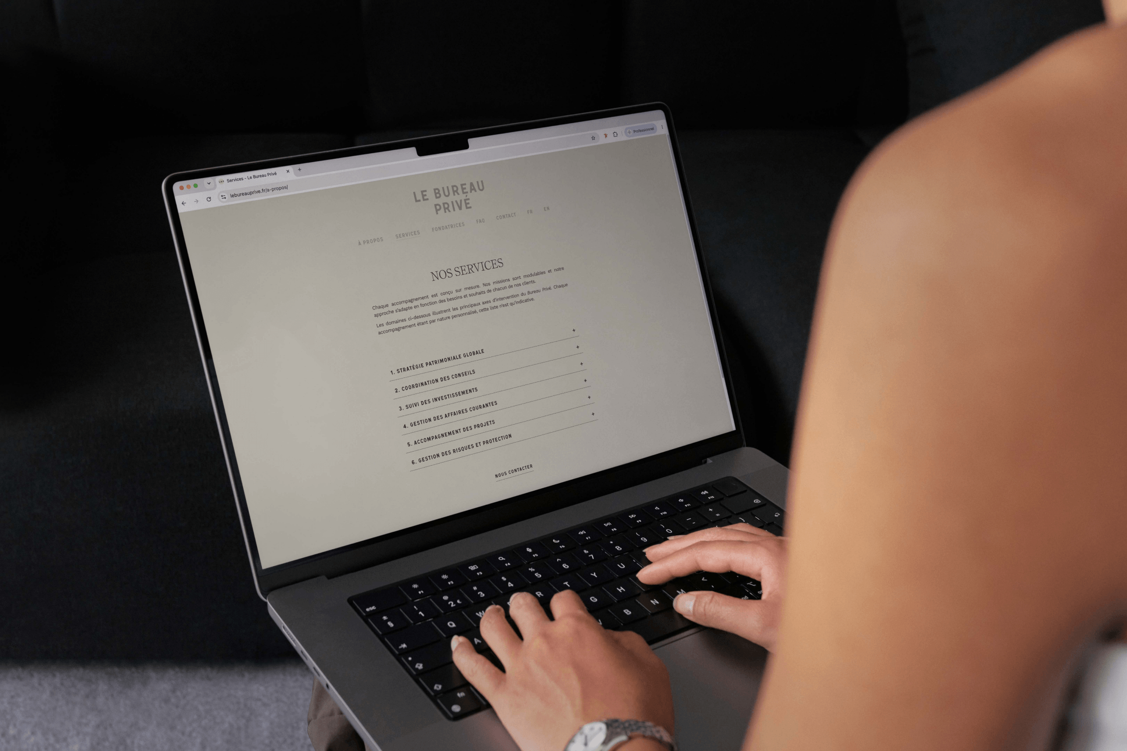 Close-up of hands typing on a laptop displaying the Le Bureau Privé website.