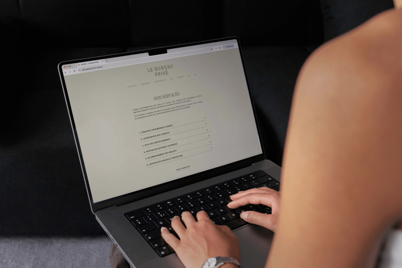 Close-up of hands typing on a laptop displaying the Le Bureau Privé website.