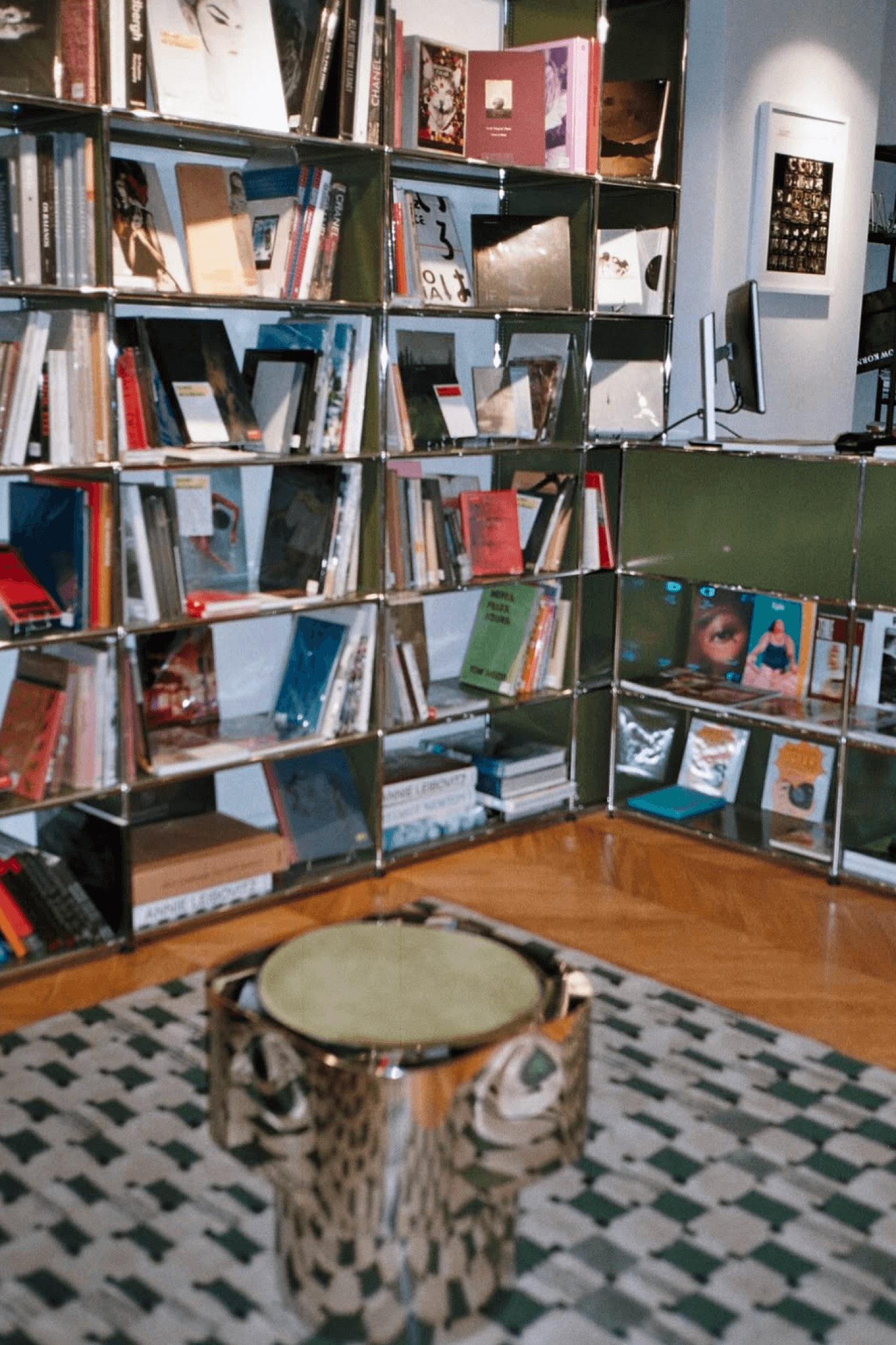 La Hune’s interior with a large bookshelf filled with books, a stool and a patterned rug.