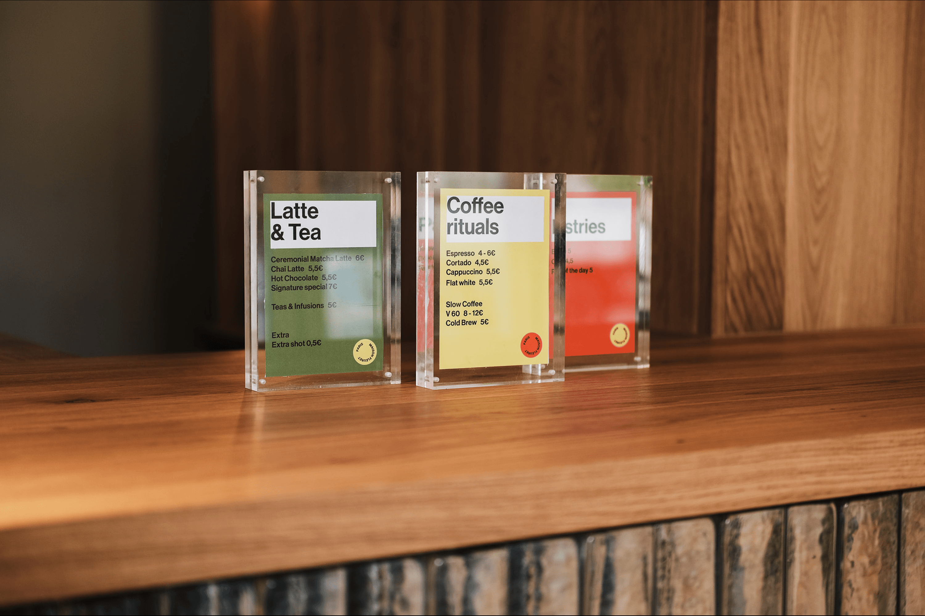 La Hune coffee menu cards displayed on a wooden counter, featuring latte, tea and coffee rituals.