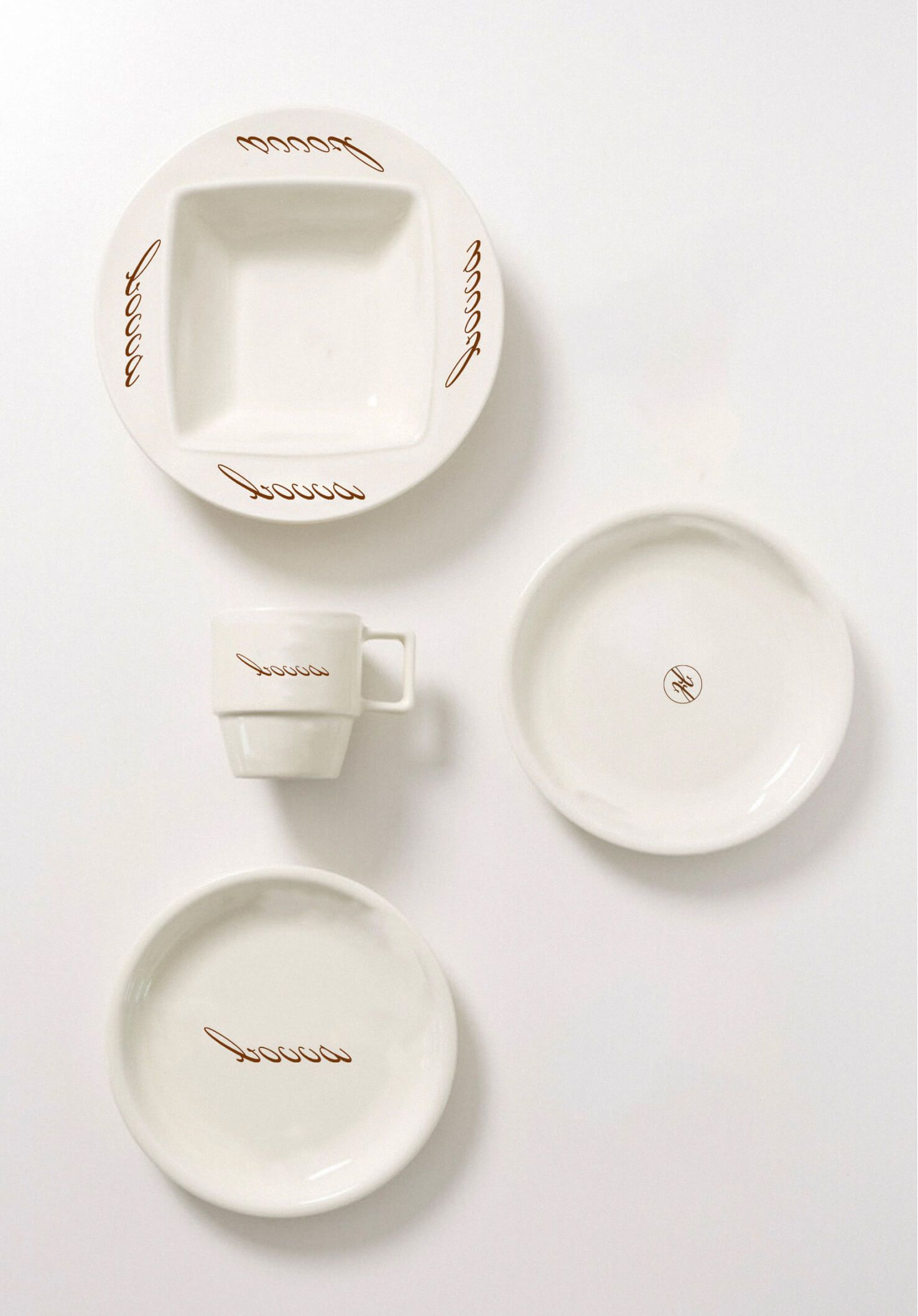Stacked white branded ceramic saucers and small plates arranged on a light surface.