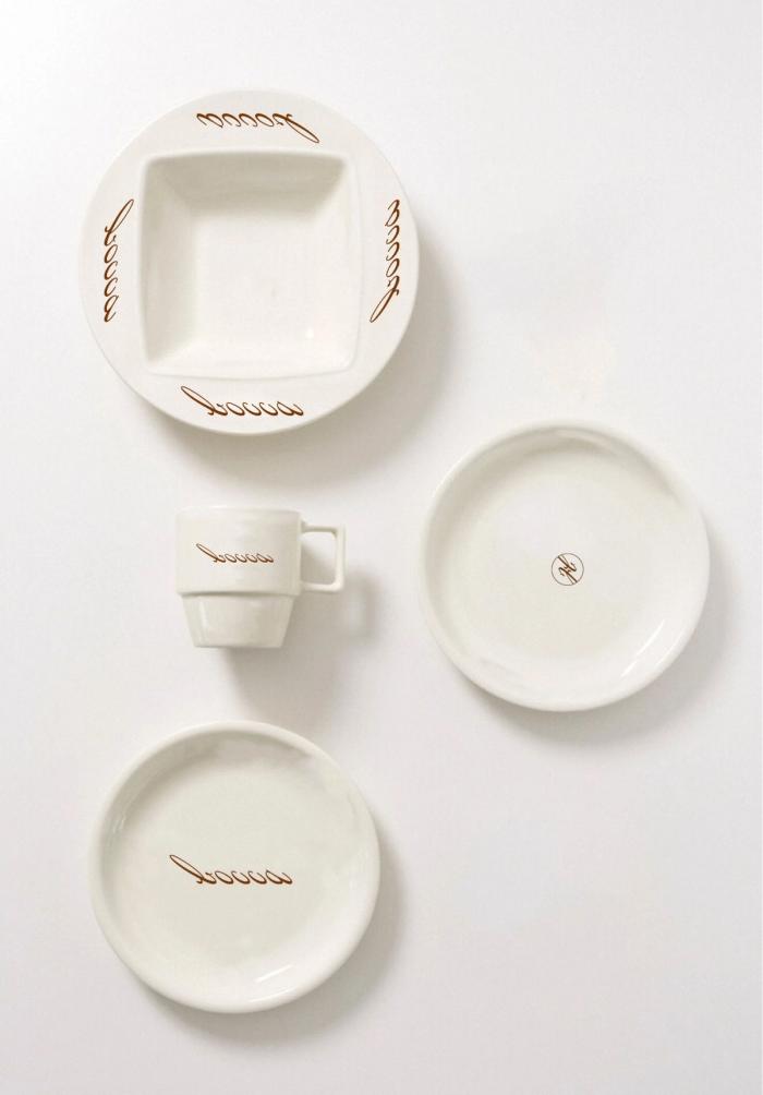 Stacked white branded ceramic saucers and small plates arranged on a light surface.