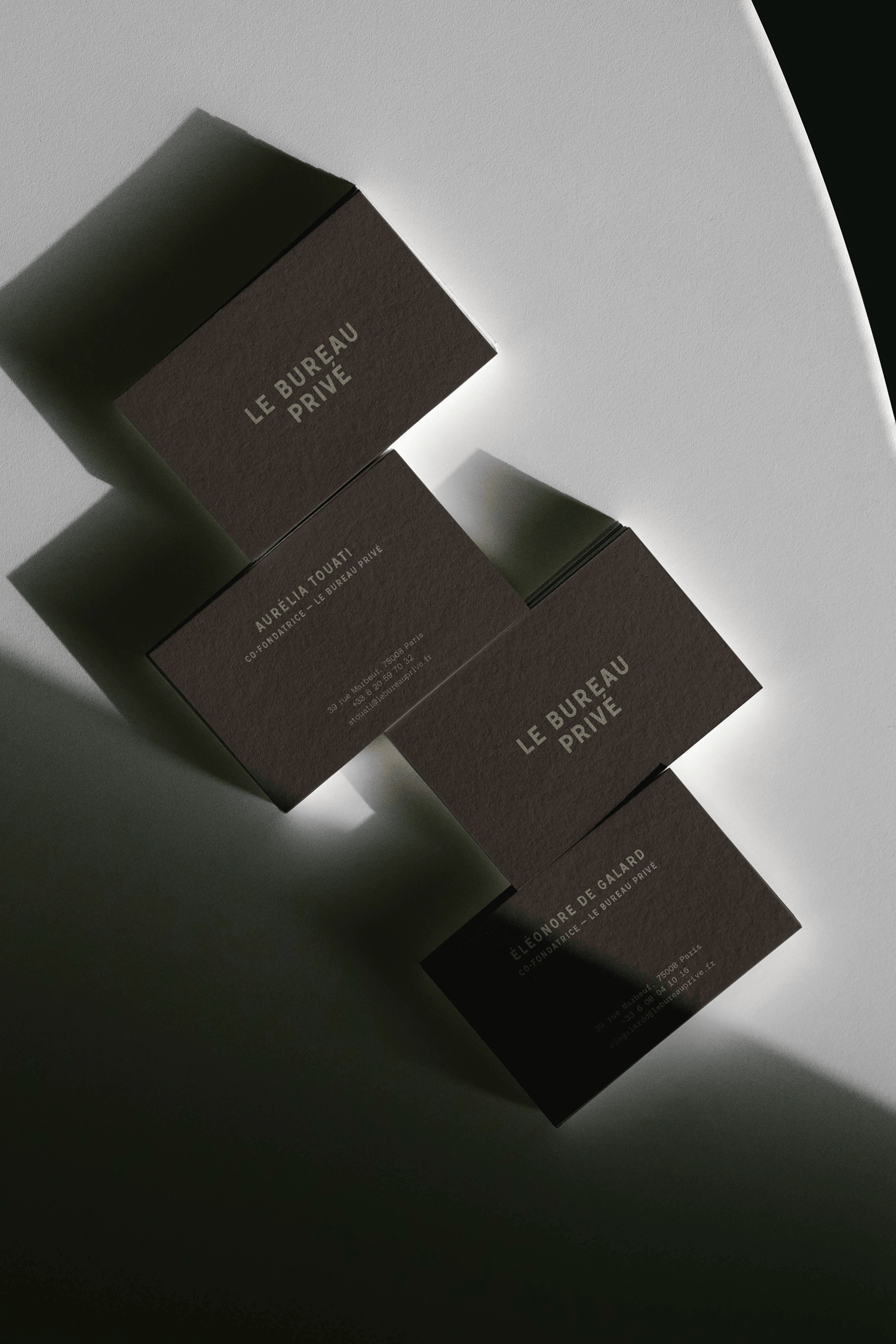 Dark brown business card boxes arranged diagonally on a light gray surface, each embossed with the "Le Bureau Privé" logo.