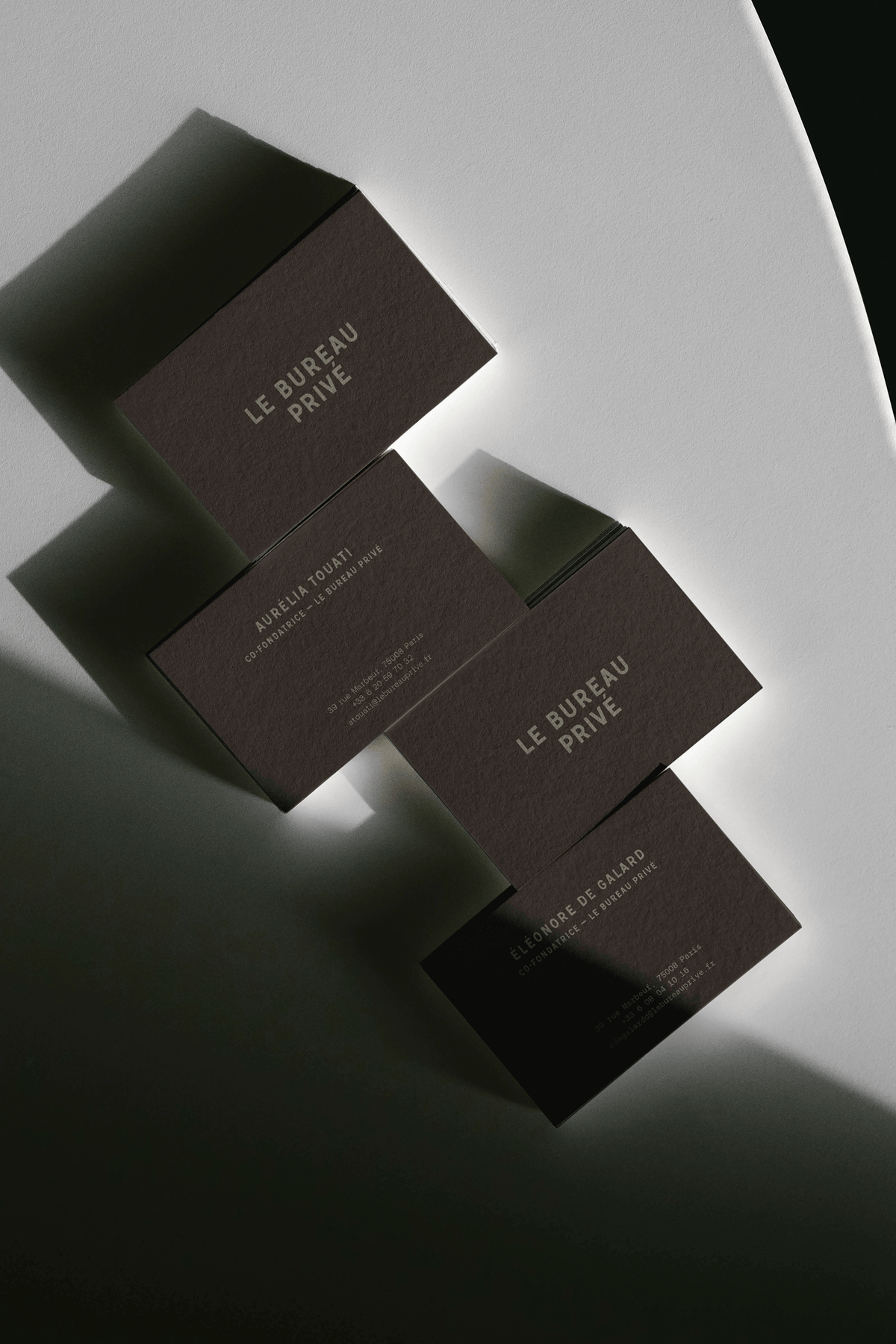 Dark brown business card boxes arranged diagonally on a light gray surface, each embossed with the "Le Bureau Privé" logo.