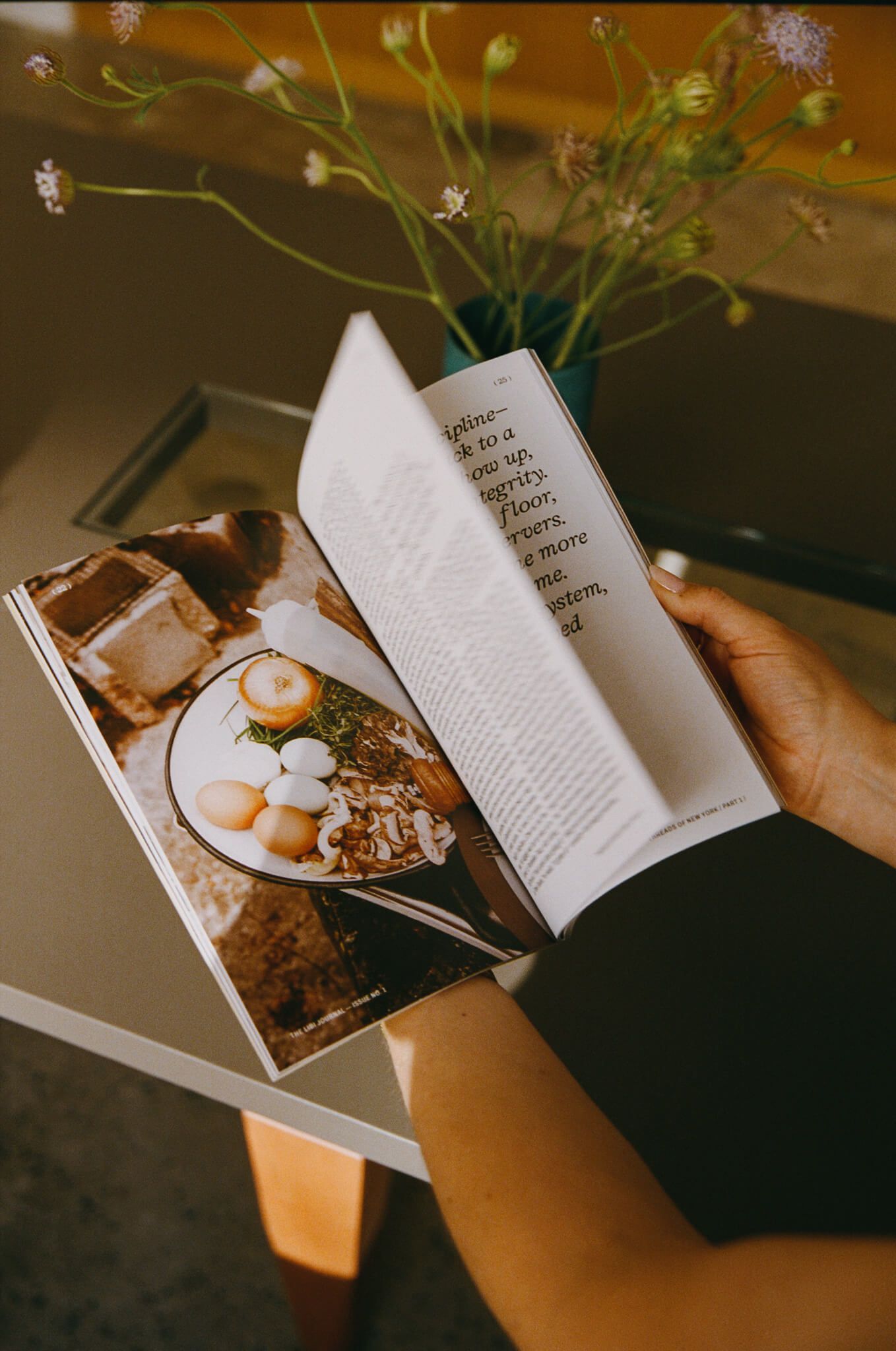 Hands holding the open journal to camera, showing a page of text opposite a photo.