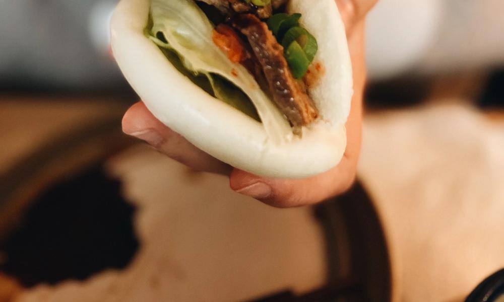 Bilde av en baobun med fyll, og en person som heller saus på