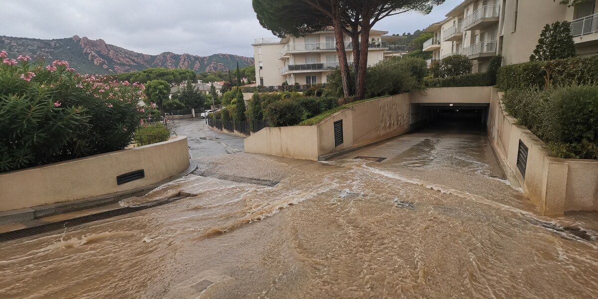 Eaux boueuses ruisselant vers la rampe d’un parking souterrain dans un quartier résidentiel méditerranéen évoquant Mandelieu-la-Napoule