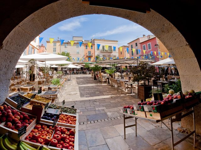 Place des Arcades à Valbonne vue sous une arche, avec façades colorées, terrasses et étals de marché