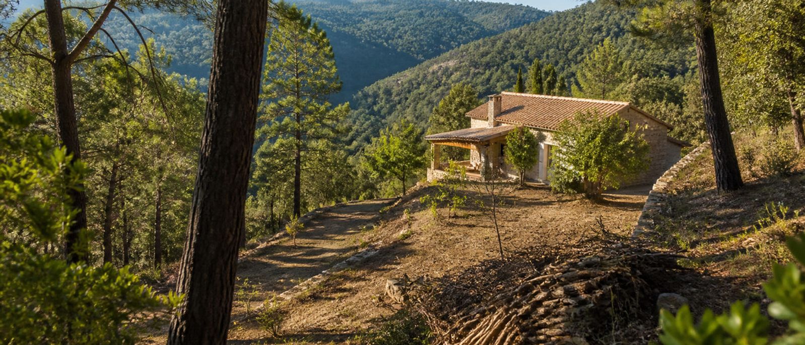 Maison en pierre entourée d’une zone boisée entretenue et débroussaillée
