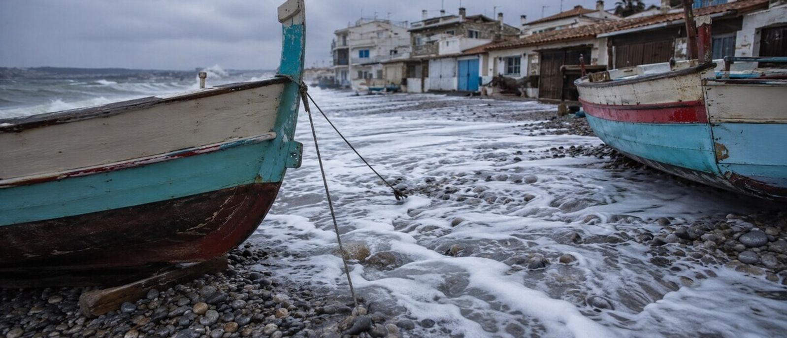 Vagues franchissant la plage de galets autour des barques traditionnelles du Cros-de-Cagnes