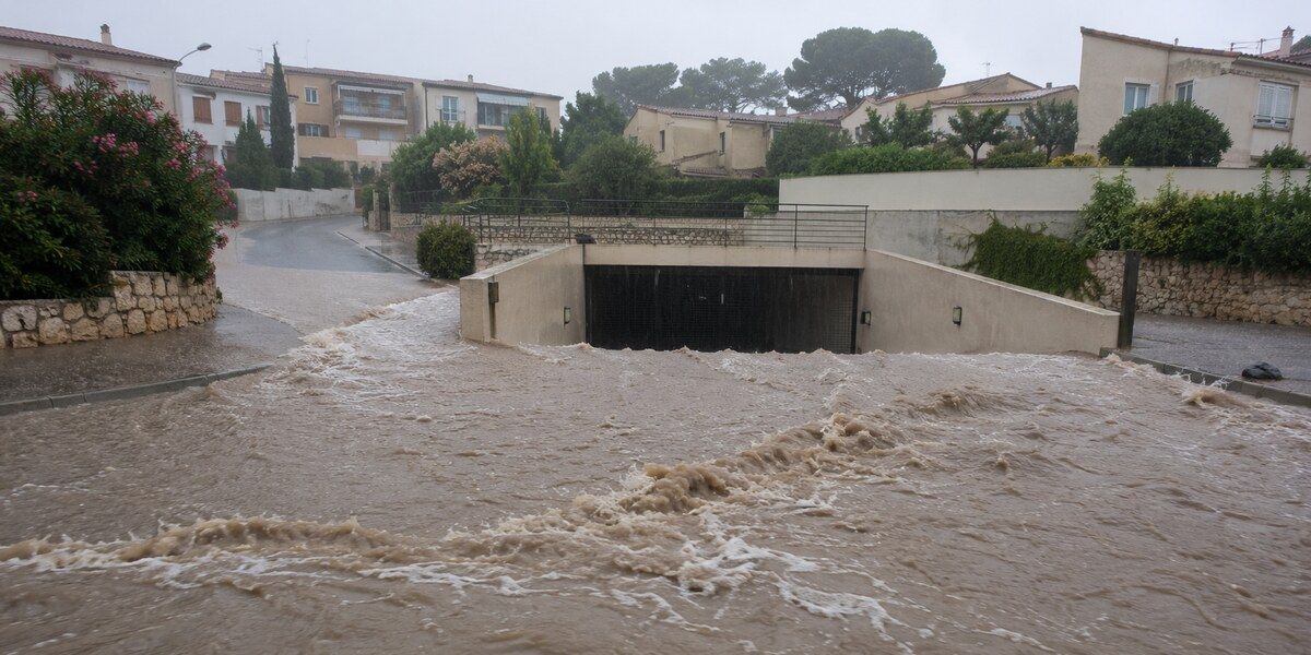 Eaux boueuses ruisselant vers la rampe d’un parking souterrain dans un quartier résidentiel méditerranéen évoquant Antibes