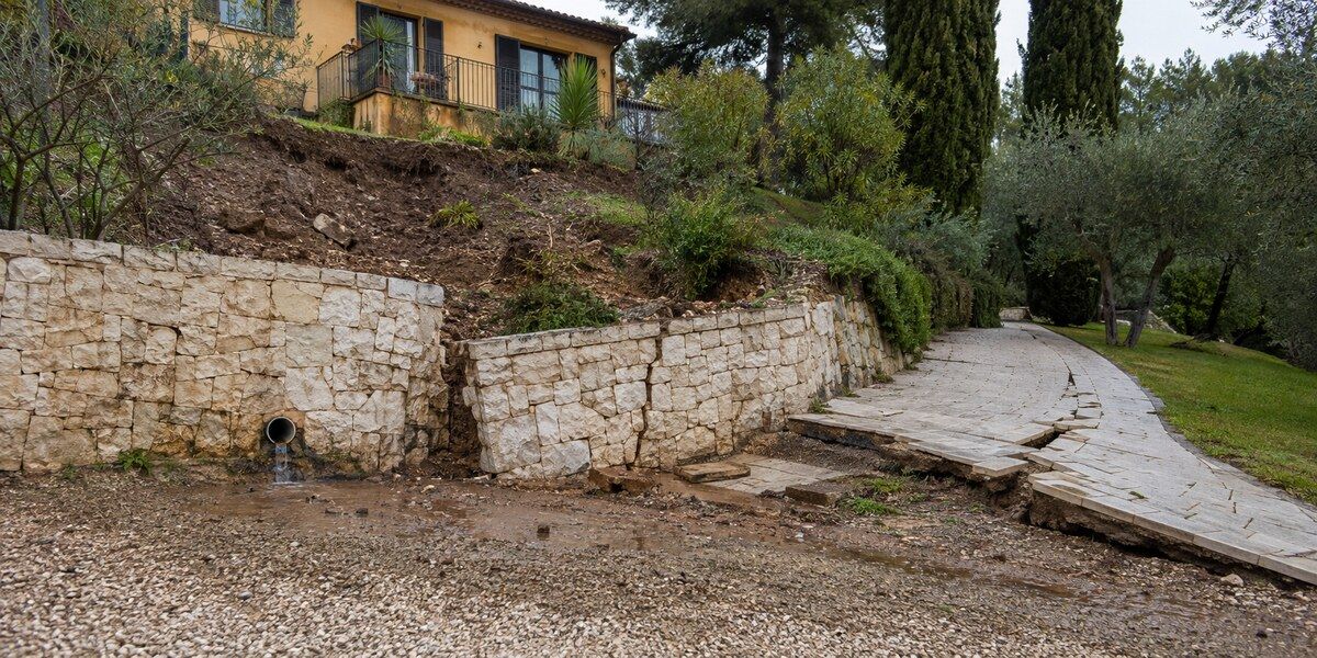 Mur de soutènement déplacé, dallage déformé et terrain glissé sur une propriété en pente évoquant les quartiers résidentiels de Mougins