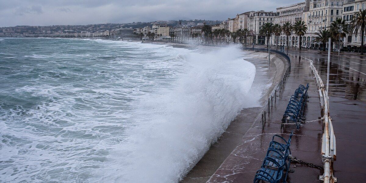 Vague de tempête franchissant le front de mer et projetant des embruns sur les chaises bleues de la Promenade des Anglais