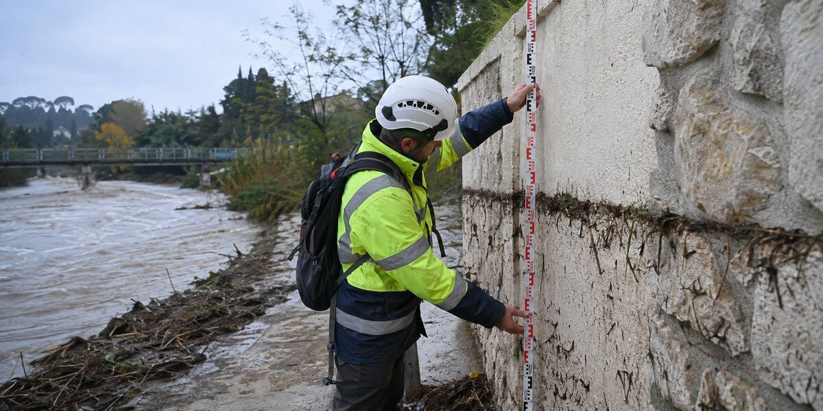 Technicien mesurant une laisse de crue boueuse sur un mur au bord du Loup à Villeneuve-Loubet