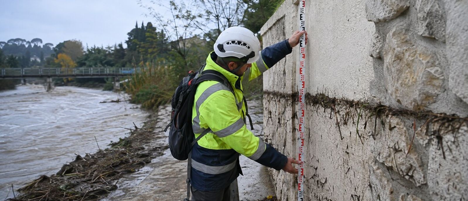 Technicien mesurant une laisse de crue boueuse sur un mur au bord du Loup à Villeneuve-Loubet