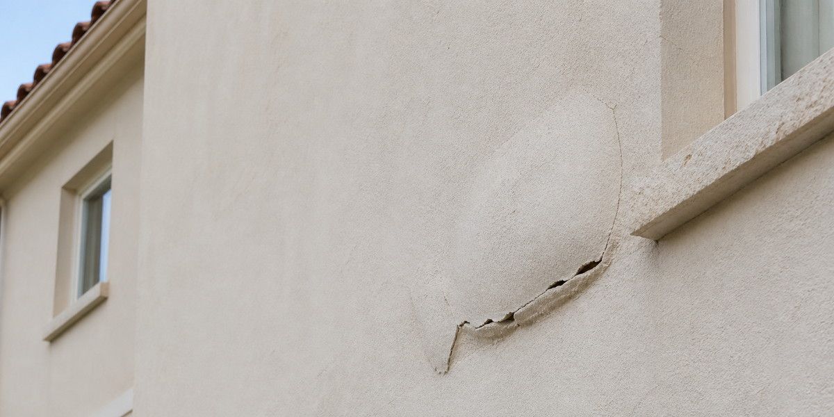 Enduit beige décollé et fissuré sur la façade d’une maison méditerranéenne