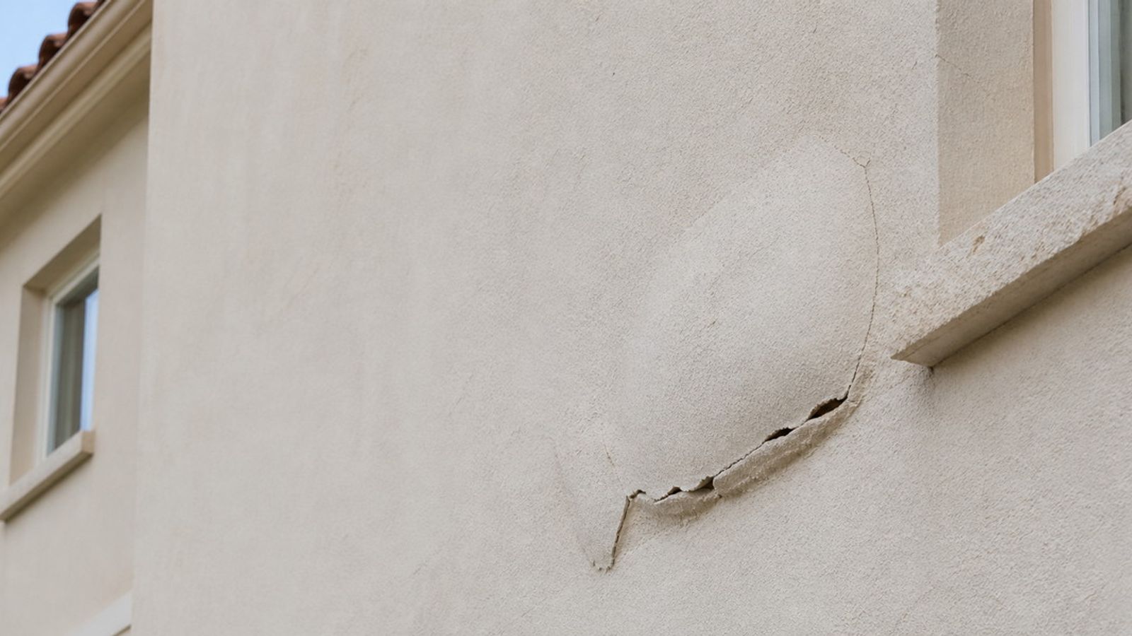 Enduit beige décollé et fissuré sur la façade d’une maison méditerranéenne