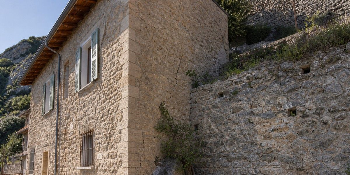 Illustration réaliste d’une maison en pierre et d’un mur de soutènement examinés en contexte sismique
