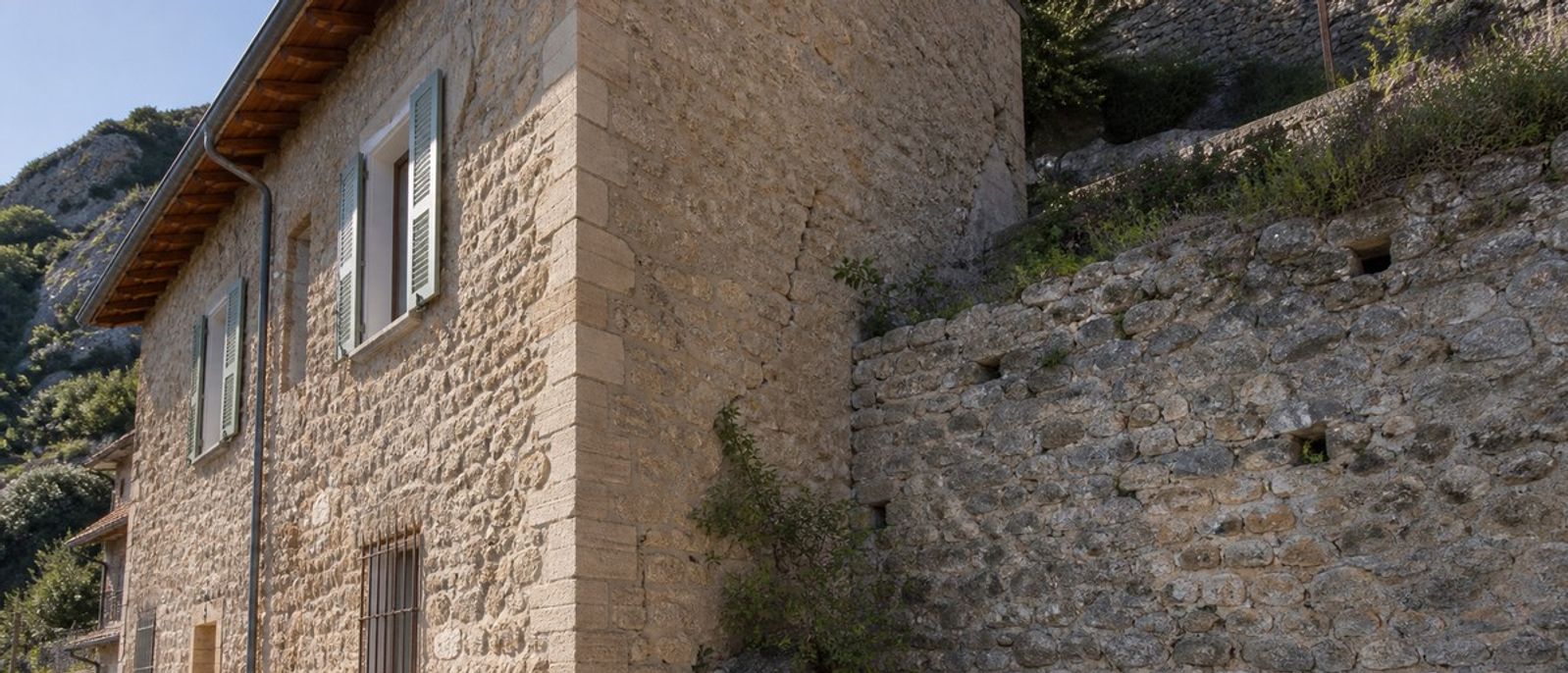 Illustration réaliste d’une maison en pierre et d’un mur de soutènement examinés en contexte sismique