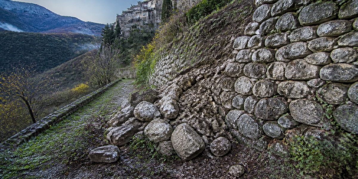 Éboulis au pied d’un mur de soutènement sur un versant boisé