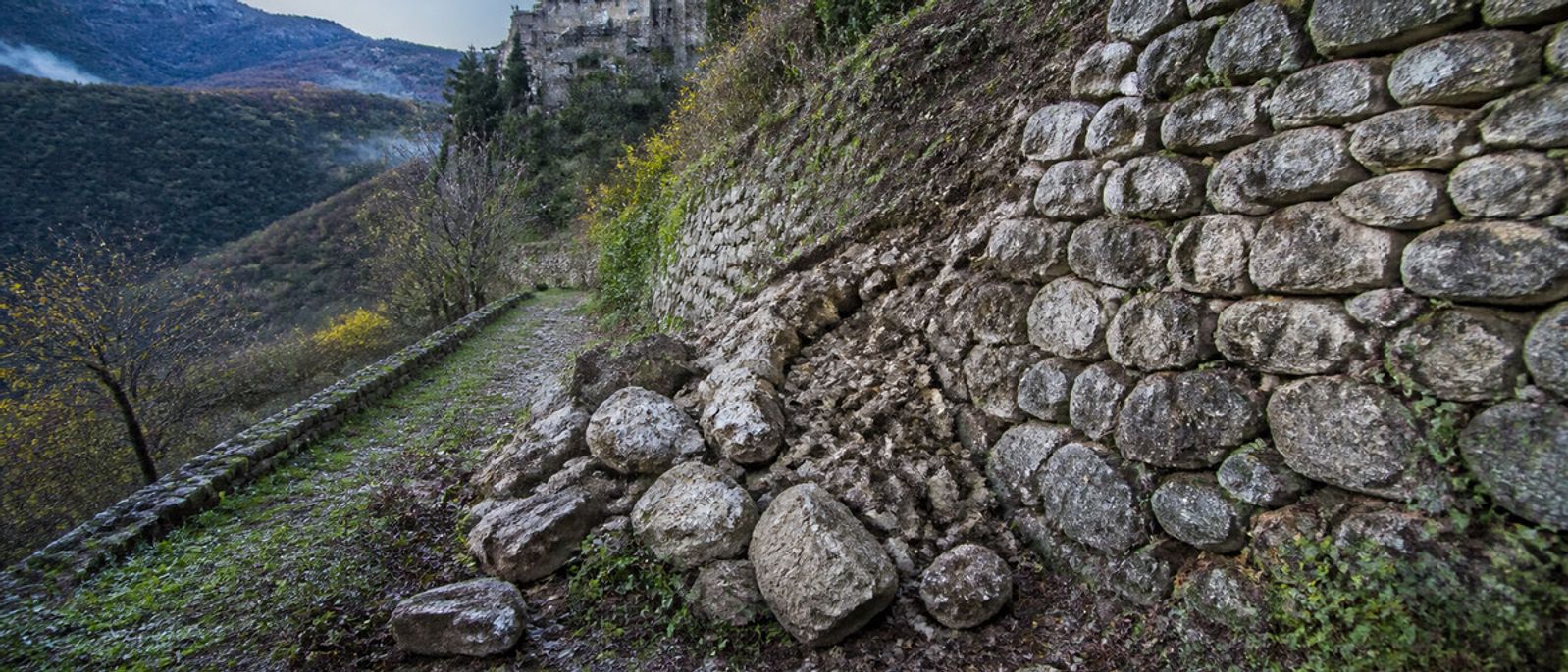 Éboulis au pied d’un mur de soutènement sur un versant boisé