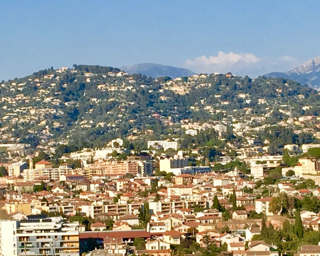 Vue de La Trinité entre centre urbanisé, coteaux bâtis et reliefs des Alpes-Maritimes