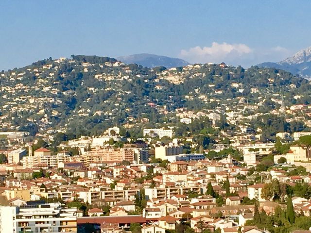 Vue de La Trinité entre centre urbanisé, coteaux bâtis et reliefs des Alpes-Maritimes