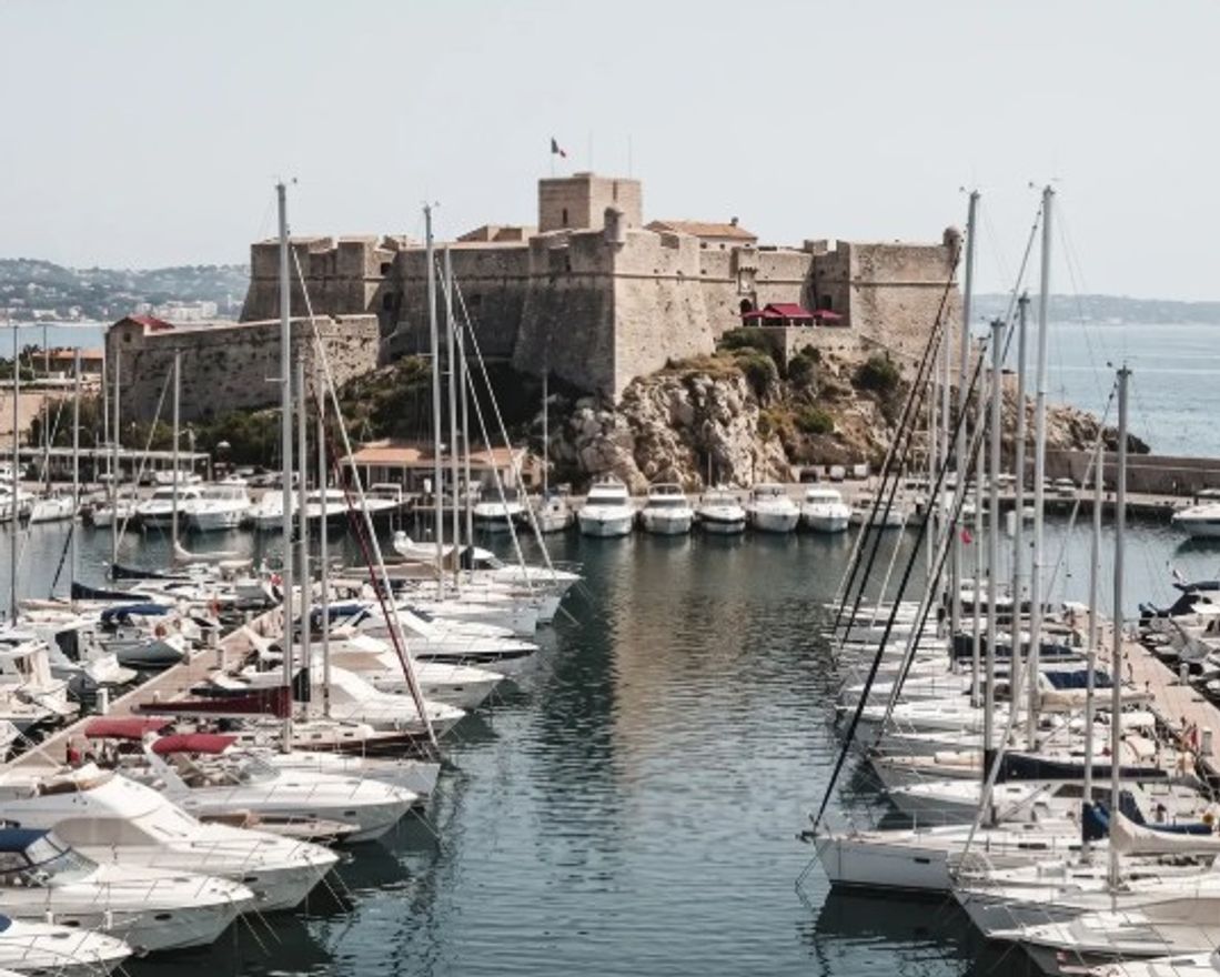 Vue panoramique du Vieil Antibes et de ses remparts dominant la Méditerranée, avec le Port Vauban, les toitures anciennes et le Cap d’Antibes en arrière-plan