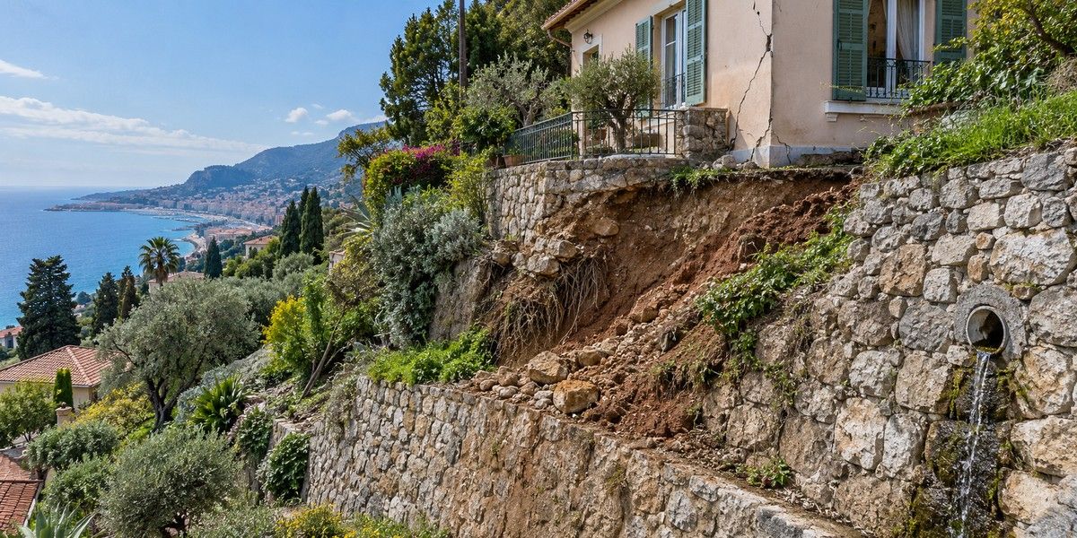Maison sur un versant de Menton avec mur de soutènement, terrain localement déstabilisé et fissure en façade