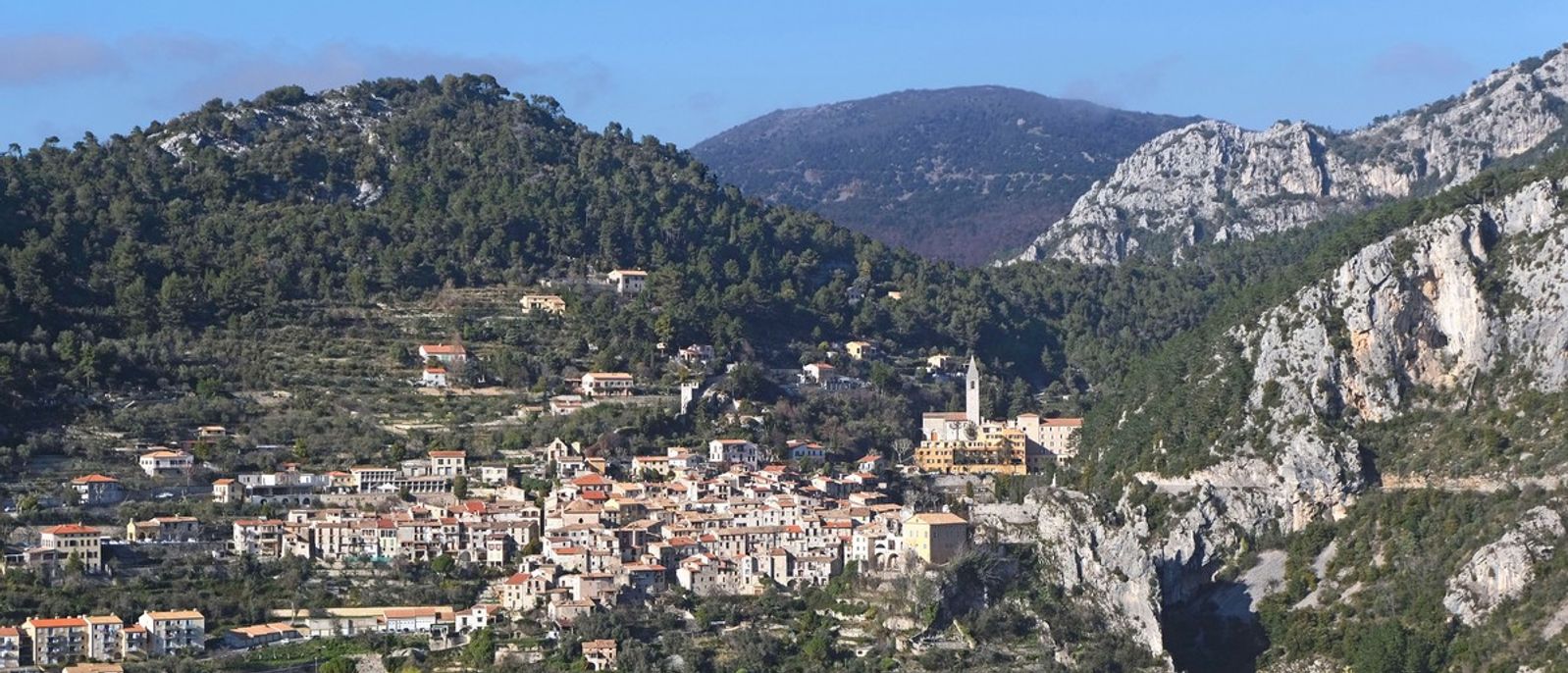 Village de Peille entouré de versants boisés et de reliefs rocheux