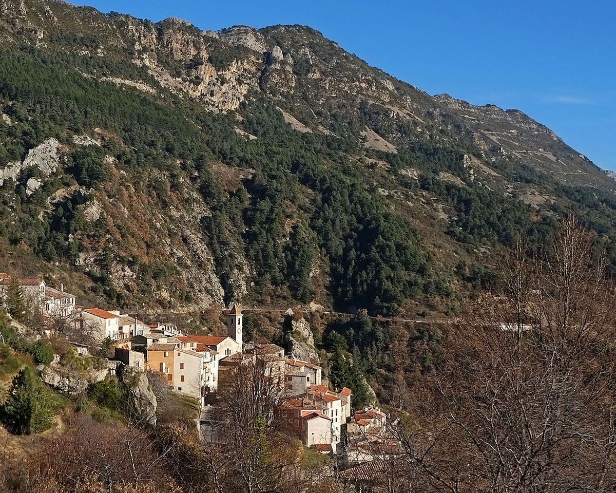 Village de Toudon au pied d’un versant montagneux boisé et rocheux