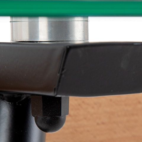 Mesa de comedor de cristal con patas negras, detalle de la unión