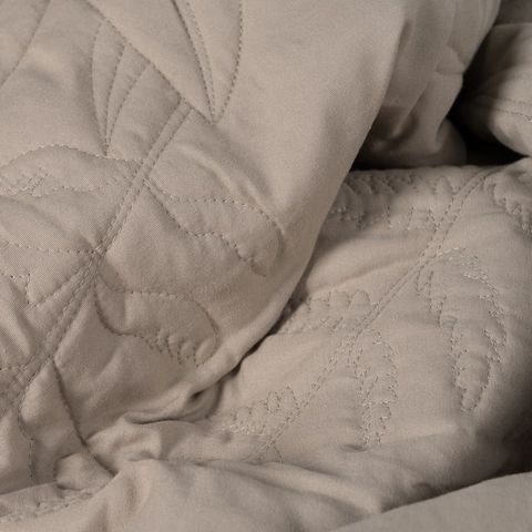 Colcha taupe con acolchado de hojas — detalle