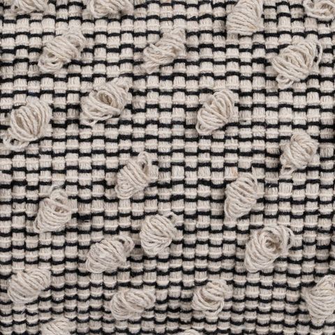 Cojín beige y negro con borlas — detalle