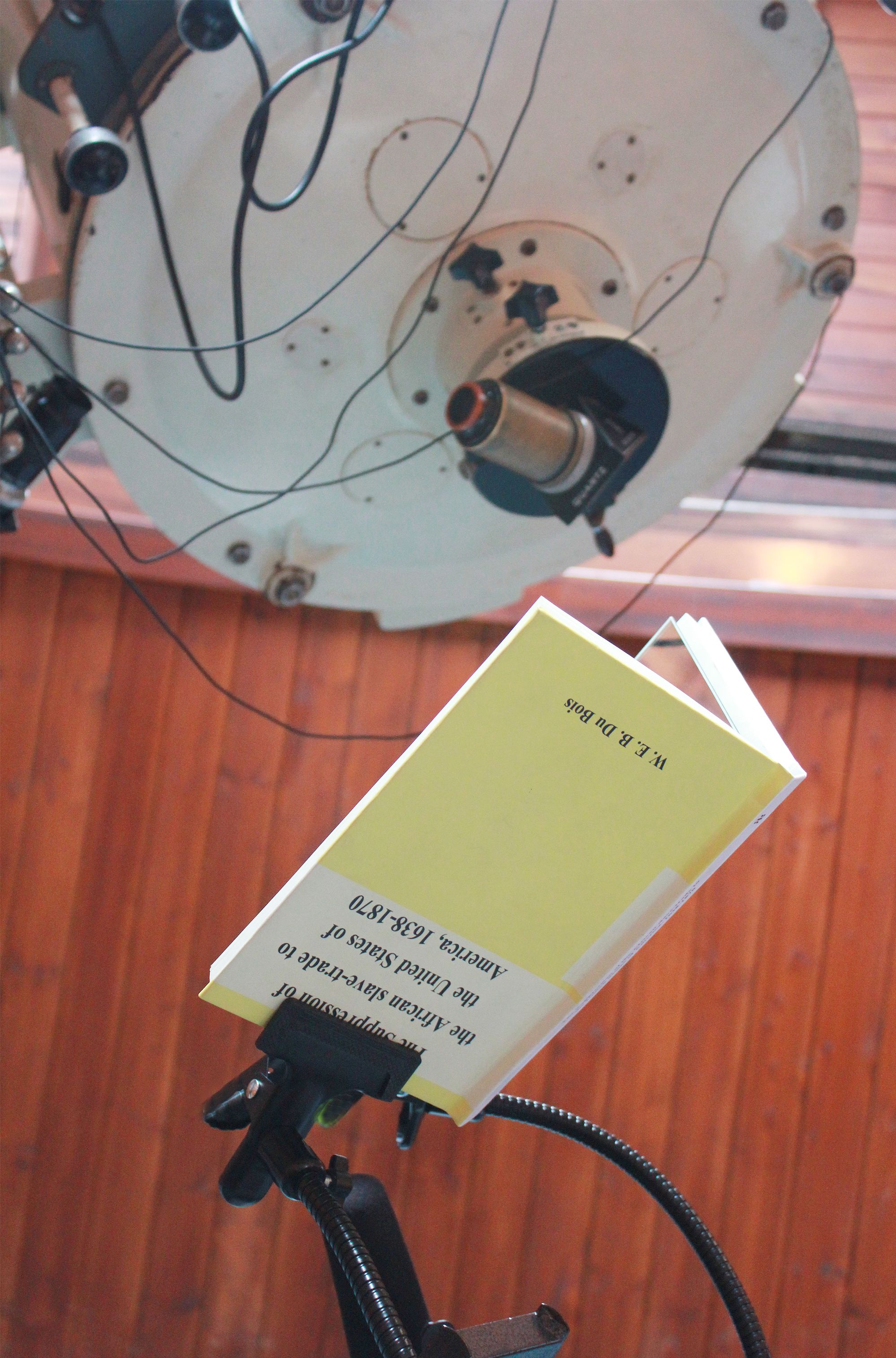 Installation view close-up of W. E. B. Du Bois book and telescope in PPKK 07.00 by Sarah Ancelle Schoenfeld and Louis-Philippe Scoufaras at Archenhold Observatory Berlin