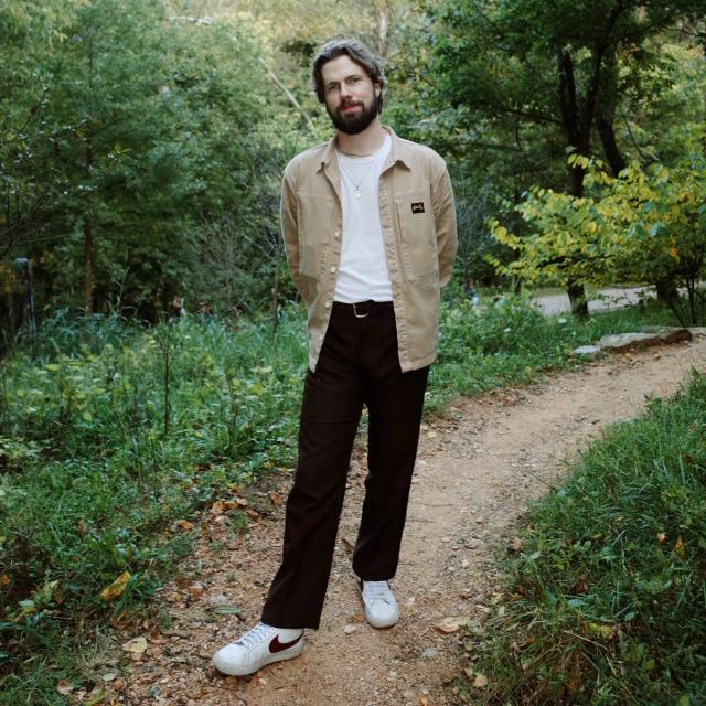 Jordan Egstad standing on a nature path near the Crystal Bridges Museum in Bentonville, Arkansas, surrounded by lush greenery and a tranquil outdoor setting.