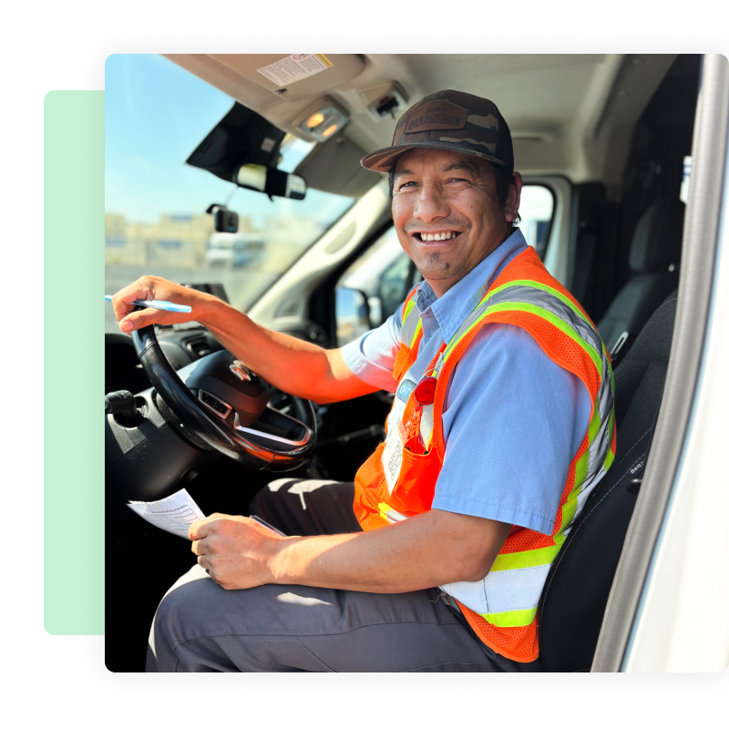 Ozark Regional Transit driver smiling in the driver’s seat of a bus, holding a paper inspection form