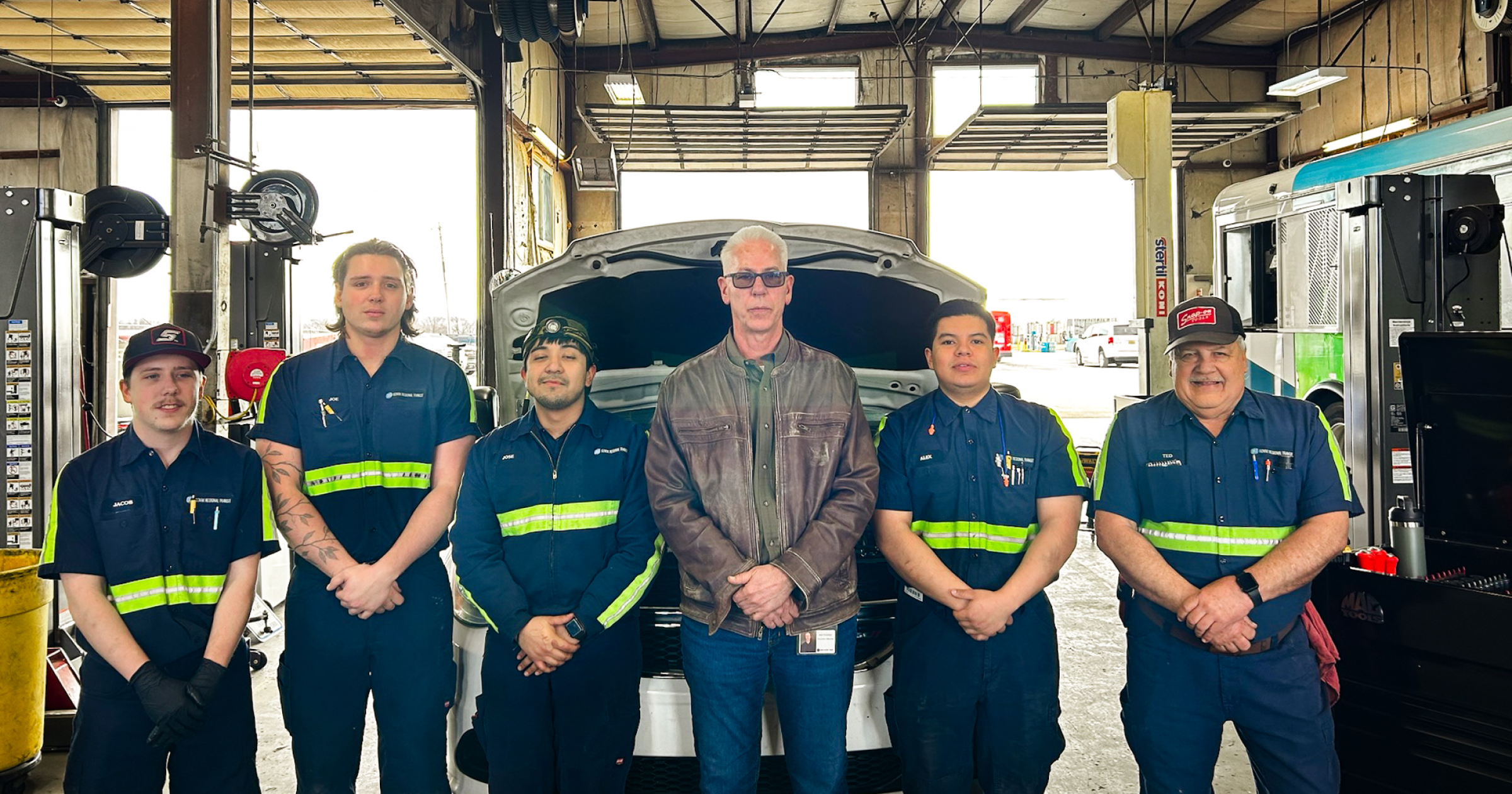 Ozark Regional Transit maintenance team standing together in a service bay in front of a bus