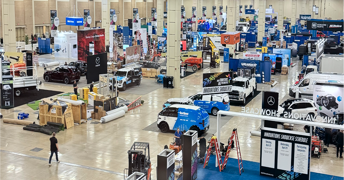 Wide view of a busy expo hall floor at a fleet management trade show, featuring booths, networking spaces, and industry displays.