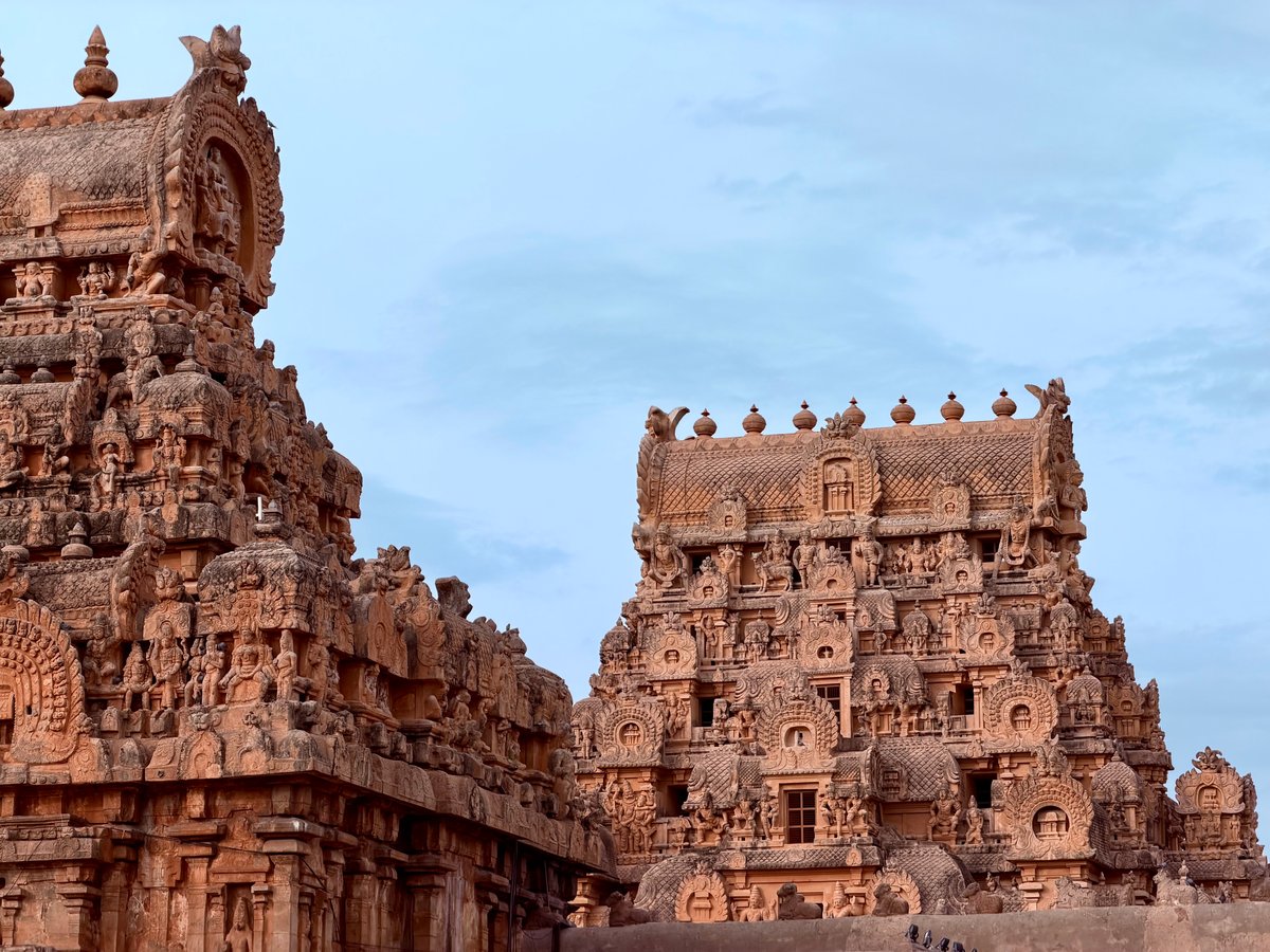 Two gopurams framed together at dusk — the inner gateways stepping you toward the sanctum. Each one a world of its own, carved with scenes that take more than one visit to read.