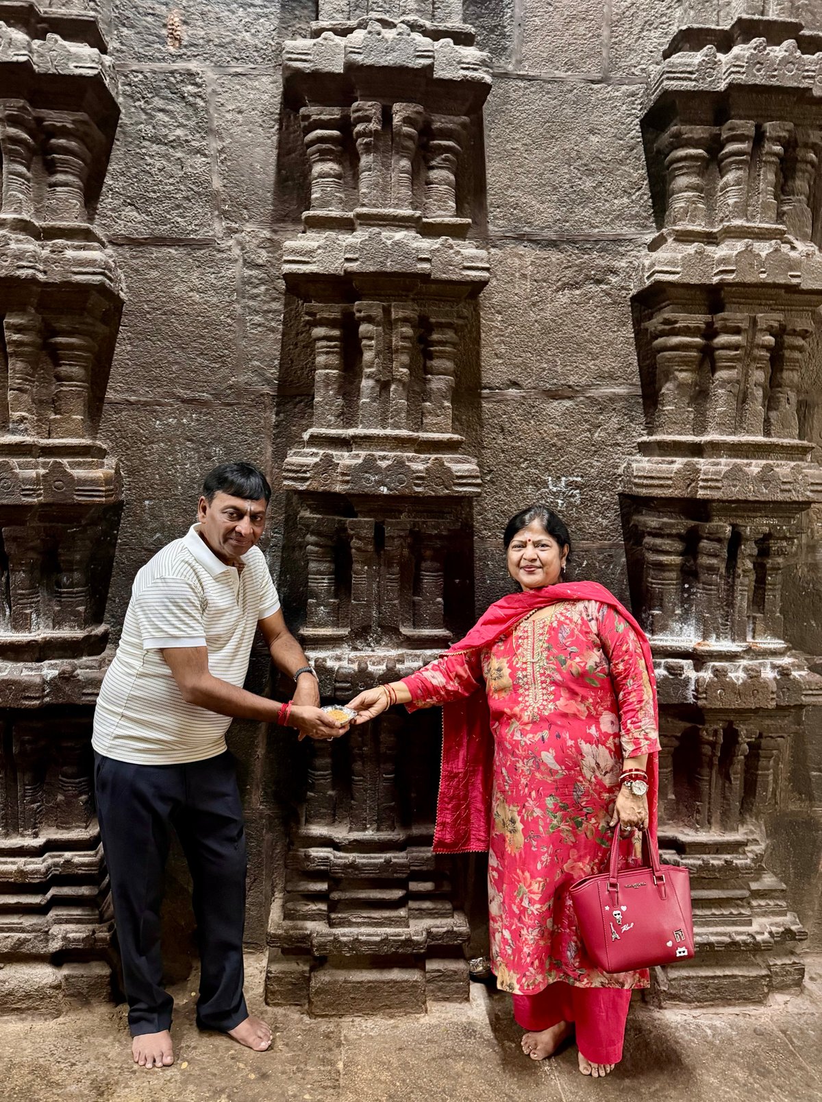 Sharing prasadam against the rock-cut wall