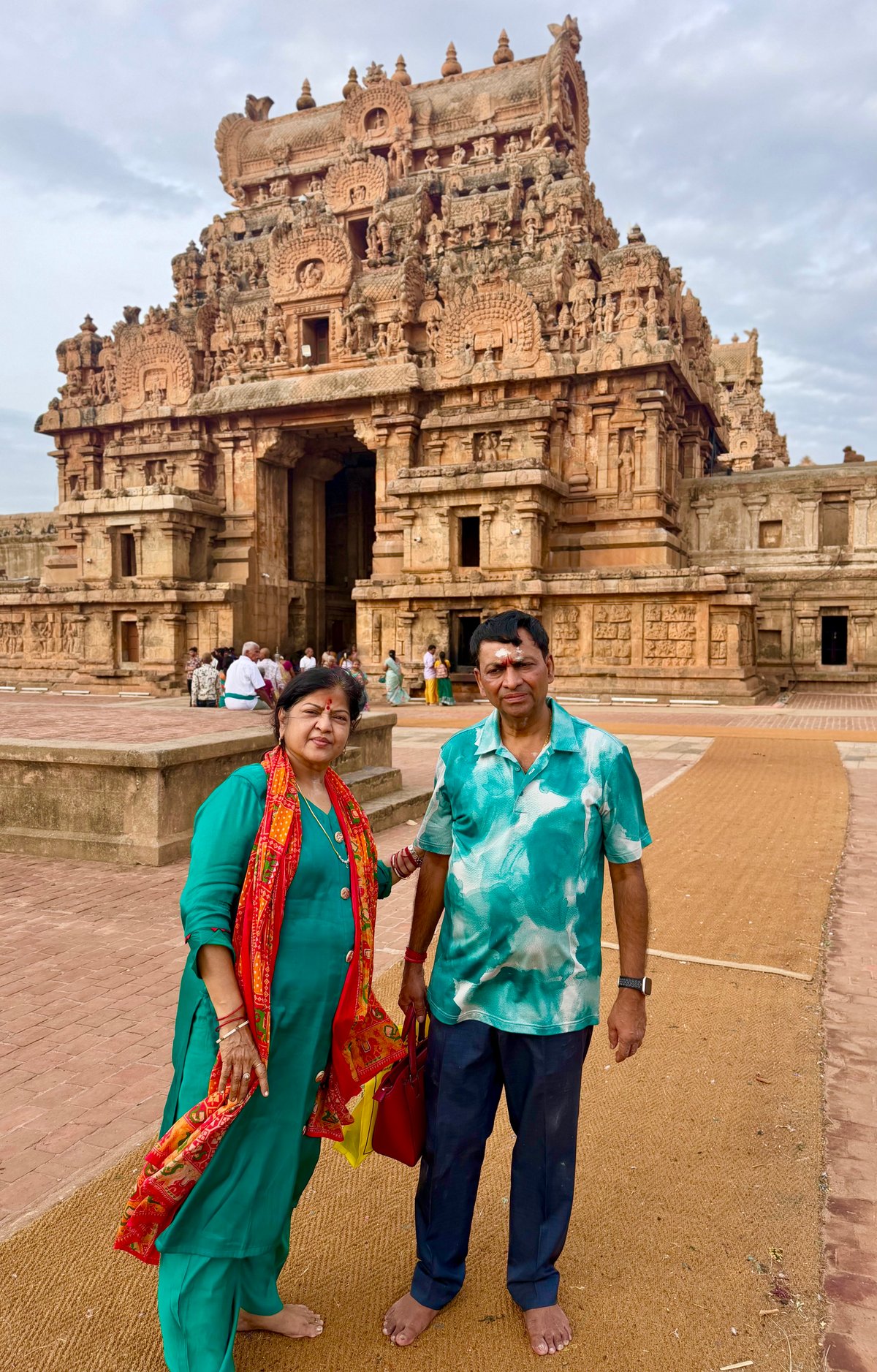 Ma and Papa at the Keralantakan gopuram — the great gateway rising behind them. Barefoot on the hot stone, the carved tower filling the sky above.