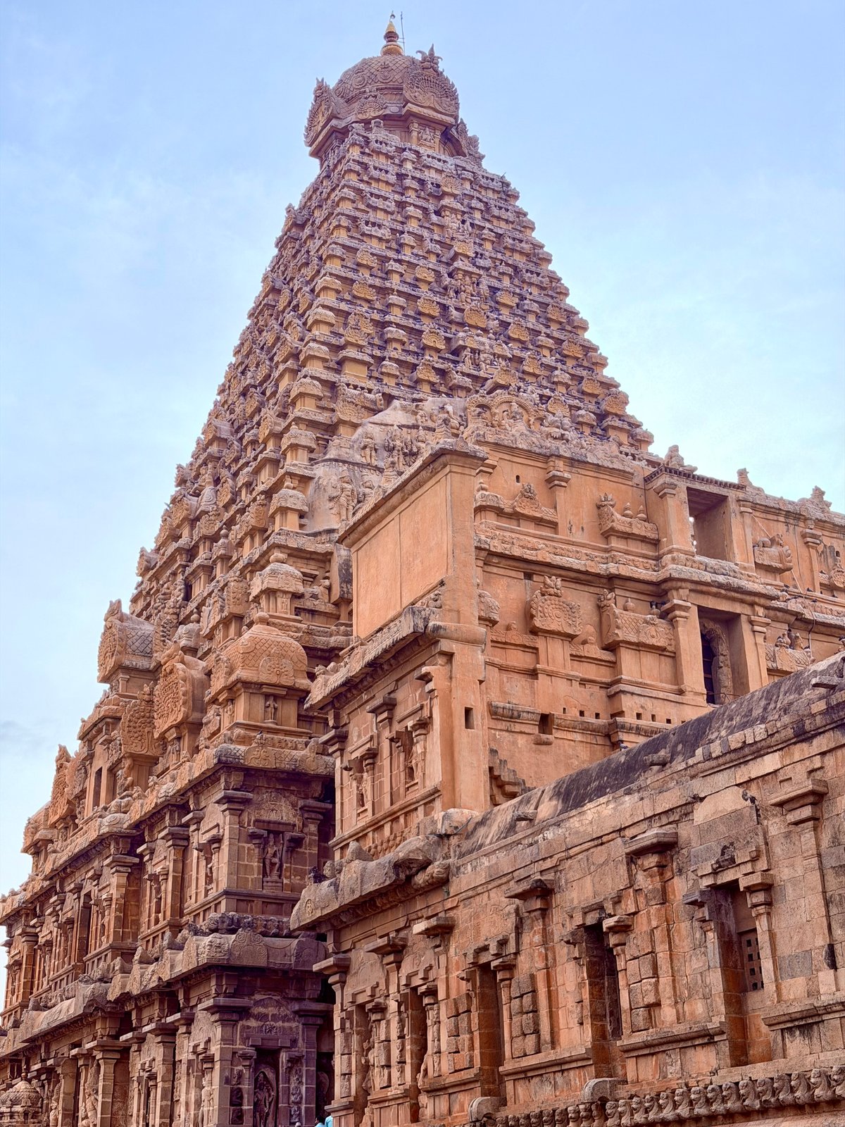 The vimana from across the courtyard — the full height visible, the mandapas and corridors spreading below. Classical Dravidian design: a square base rising to a single towering point.