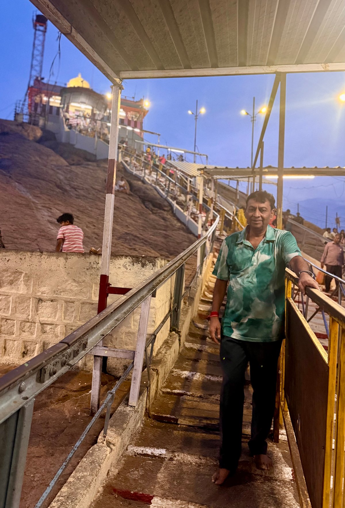 Halfway up Rockfort at dusk, the city of Trichy spread out below, the golden dome of Ucchi Pillayar glowing at the summit above. The climb is steep but the view resets something in you.