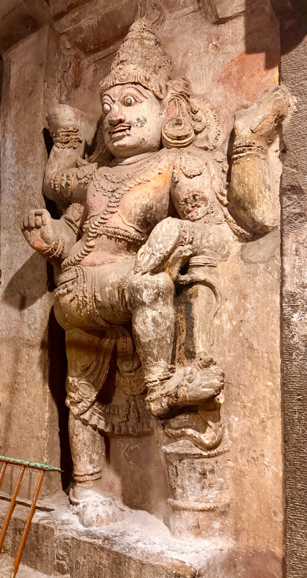 A Chola dvarapala — the temple's guardian, carved around 1010 CE. Multi-armed, fierce-eyed, his pose unchanged for a thousand years. You pass him every time you enter.