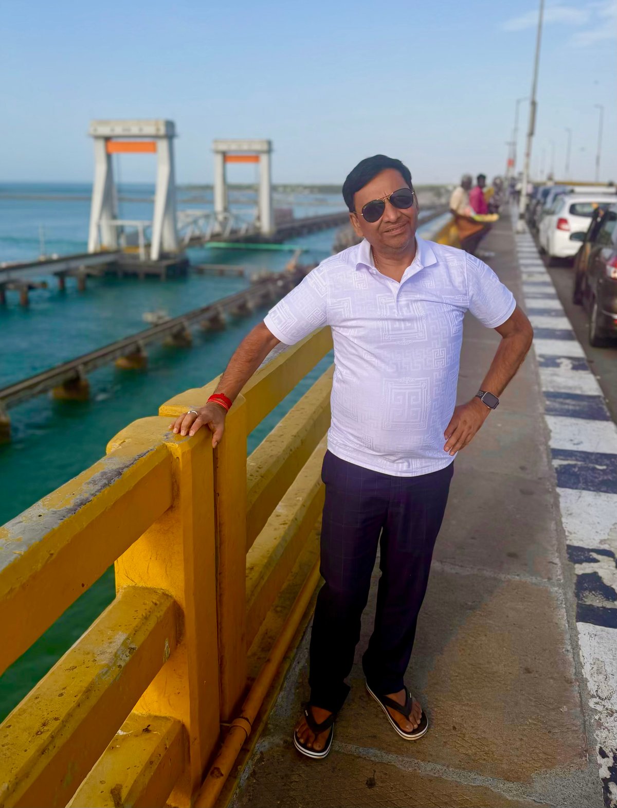 Papa on the Pamban Bridge — India's first sea bridge, stretching 2 km across the Palk Strait to connect Rameswaram island to the mainland. The bascule section that lifts to let ships through is visible behind him, the turquoise sea on either side.