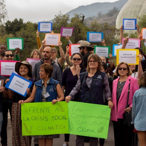 Personas con carteles sobre la crisis social y climática frente al Templo