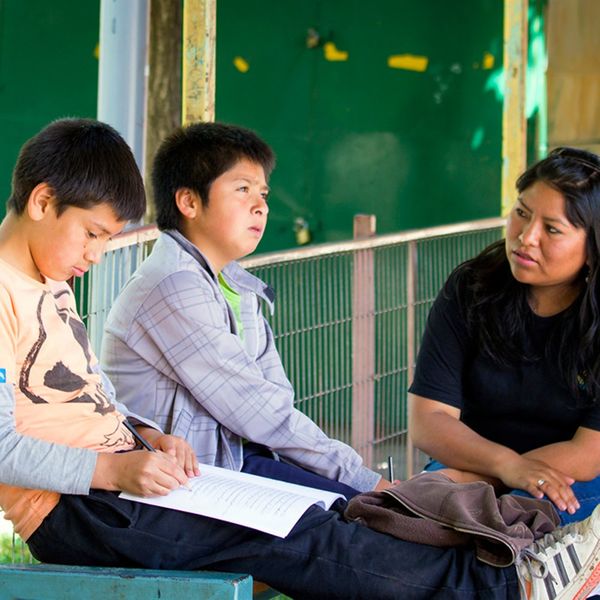 Dos prejóvenes conversan y escriben junto a una facilitadora